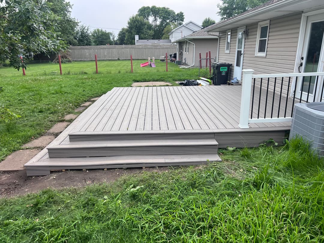 Composite deck installation in backyard with grass and nearby house visible.