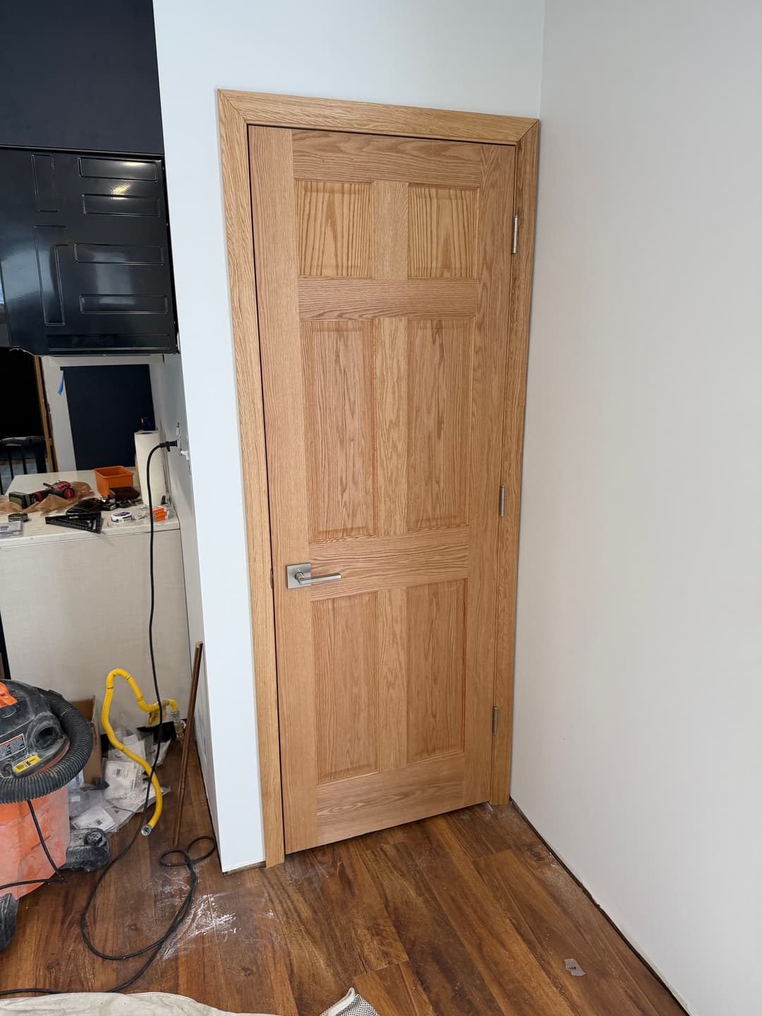 Oak interior door with five panels and sleek metal handle, featuring a modern home setting.